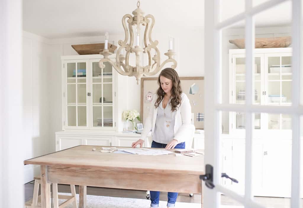 Home office with white cabinets and large desk with woman working