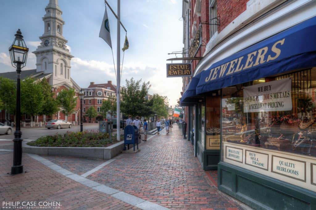 A storefront with a blue awning on a brick street in Market Square in Portsmouth, NH