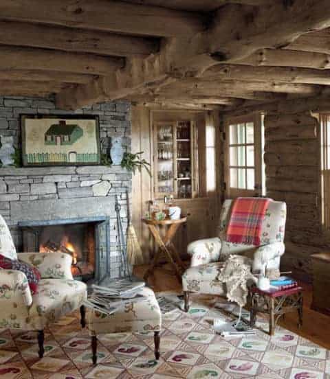 A living room in a rustic New England log cabin with a fireplace.