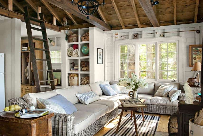 A living room with wooden beams and wicker furniture inspired by New England cottage home style.