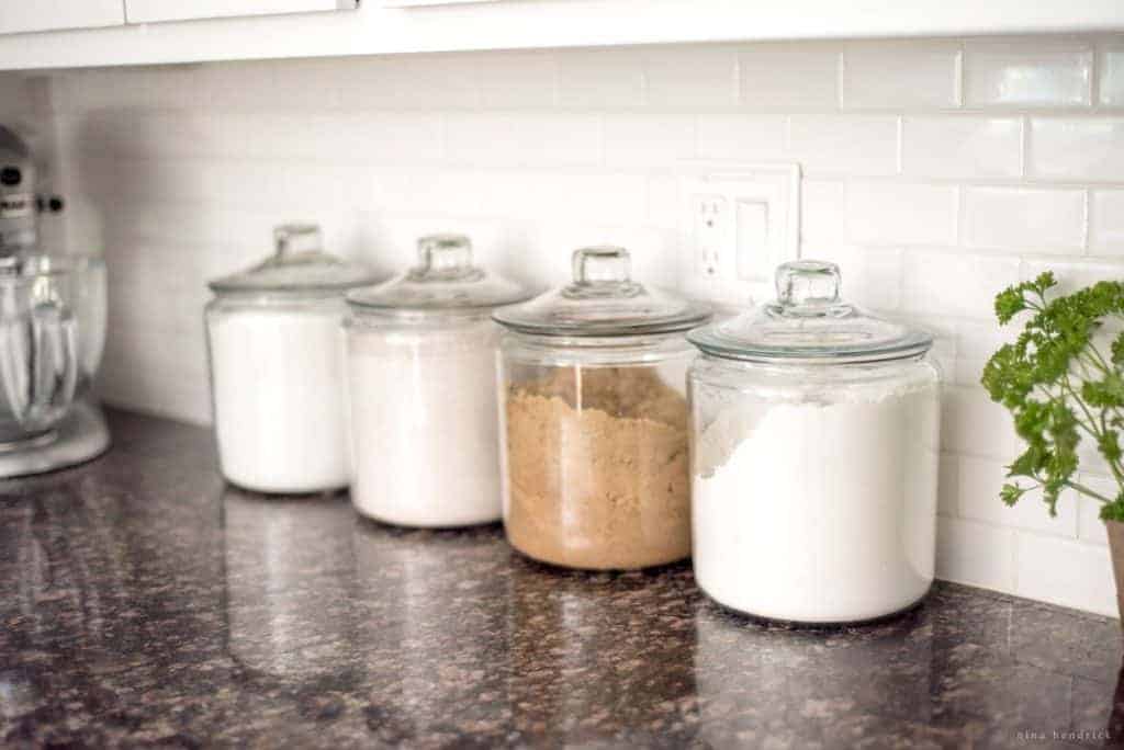 Leaving baking and coffee canisters out can help add character to a white kitchen.