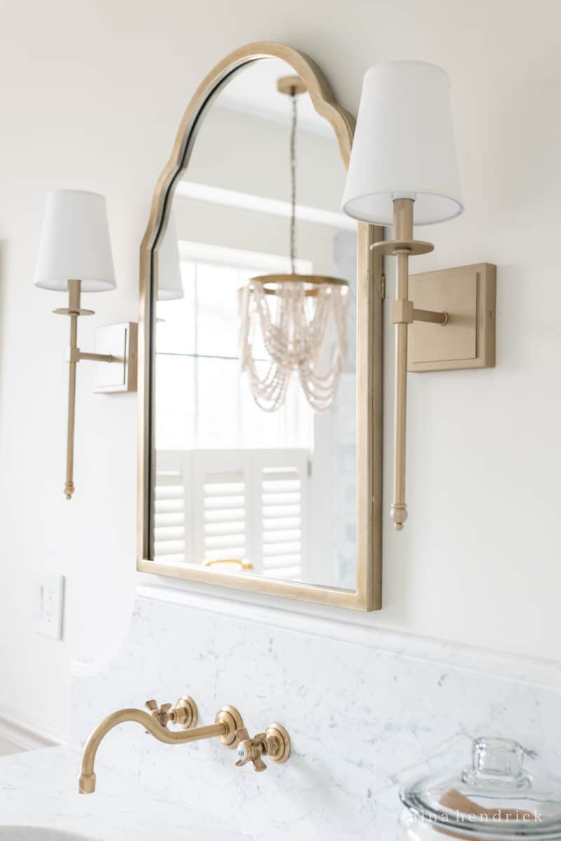 Bathroom lighting design ideas, brass sconces and a wood bead chandelier over the tub