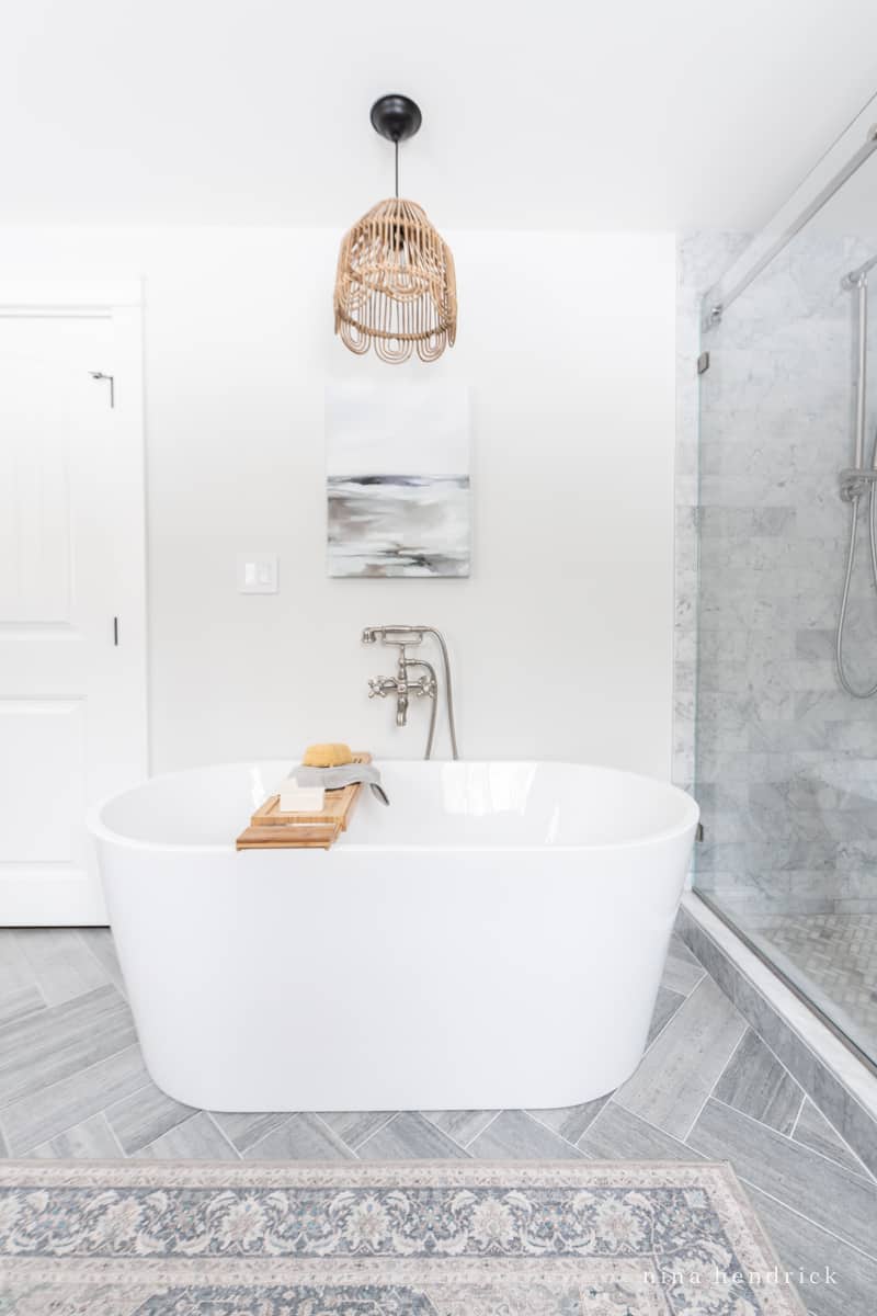 Freestanding tub with coastal art and a light fixture