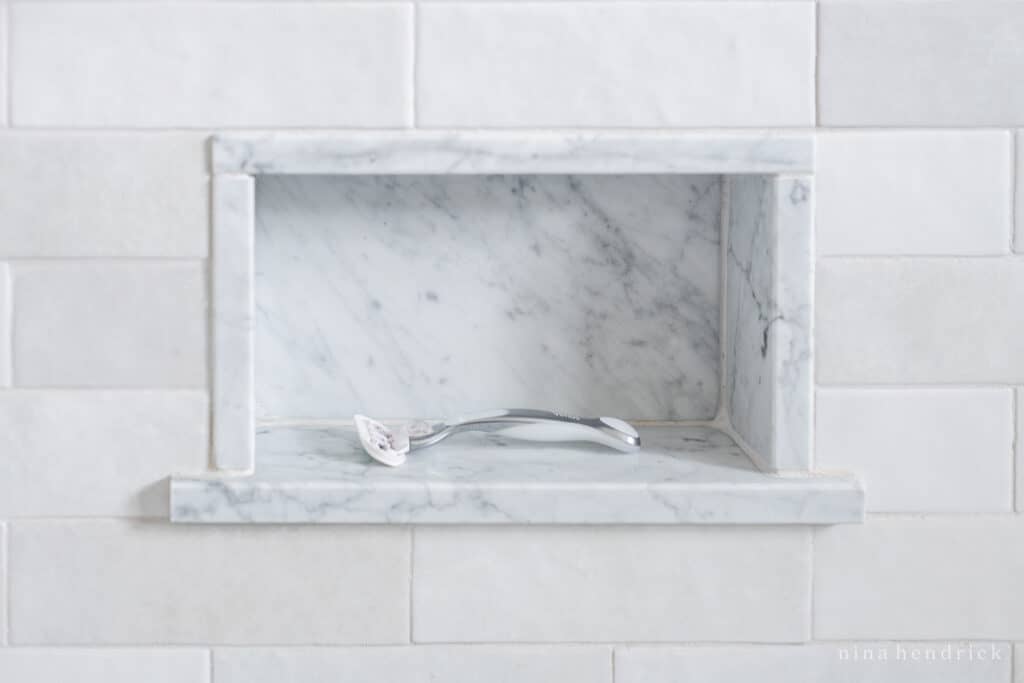 Marble shaving niche installed in shower for easy leg shaving and razor storage