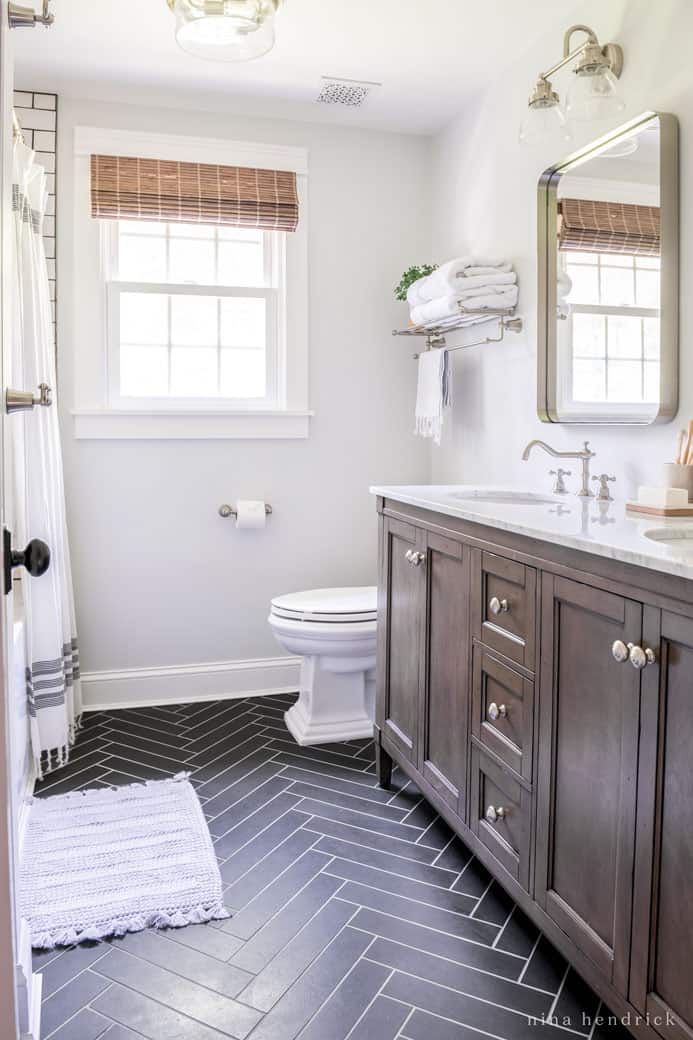 Modern bathroom design ideas like herringbone tile, deep metal mirrors, and contrast between the dark floors and white walls