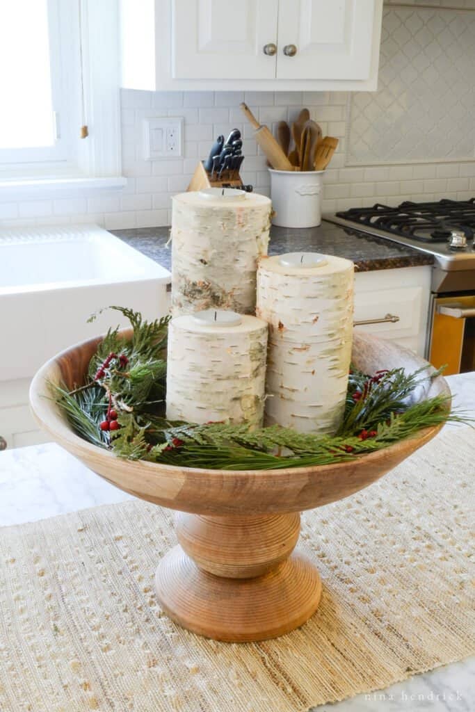 DIY birch log candle holder arrangement in wooden bowl with greenery