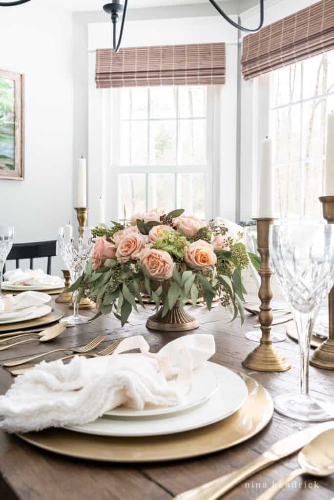 Blush Valentine's Day tablescape with gold chargers, candlesticks, and flatware.