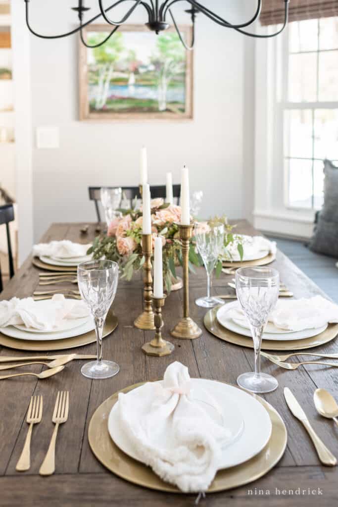 Gold place setting with white plates and a linen napkin with blush ribbon.