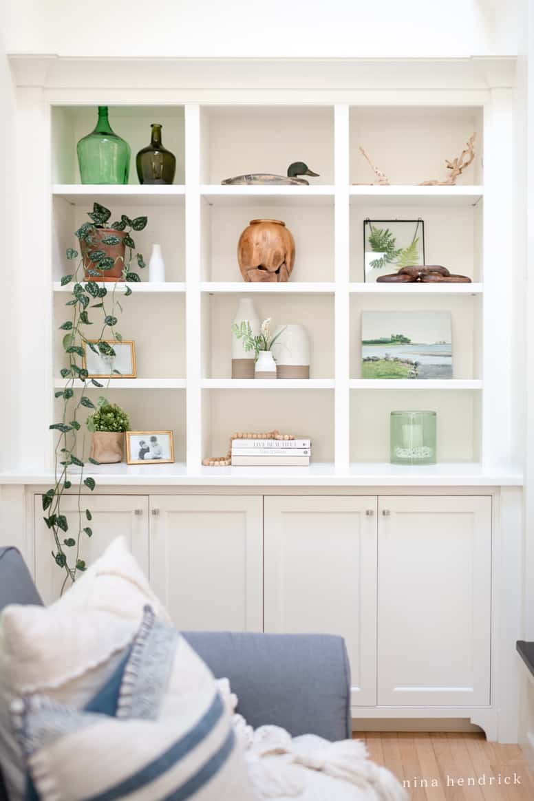 White bookshelf with small shelves full of coastal decor and plants