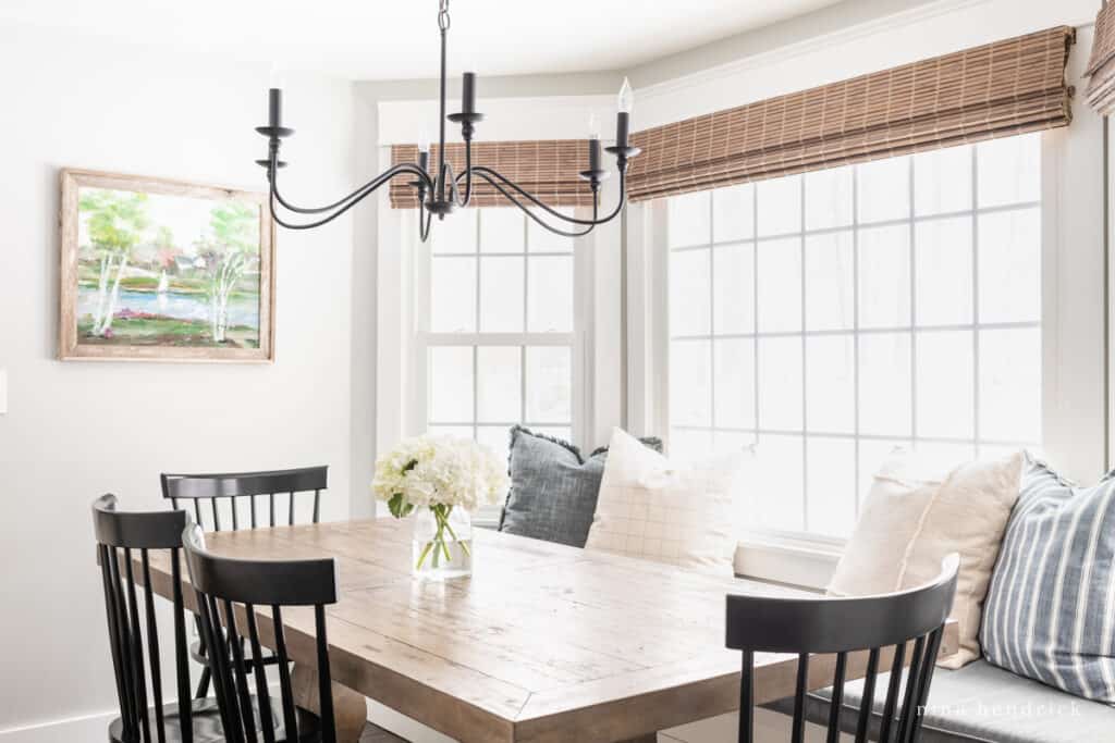 Dining room table with iron chandelier and throw pillows