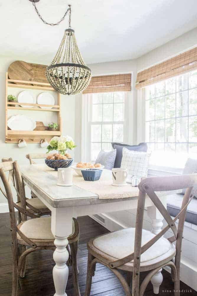 Image take of breakfast nook angled down the length of dining room table with chairs