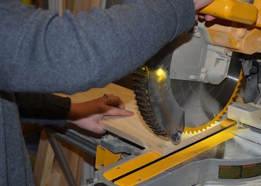 Cutting a shelf board length-wise with a compound miter saw.