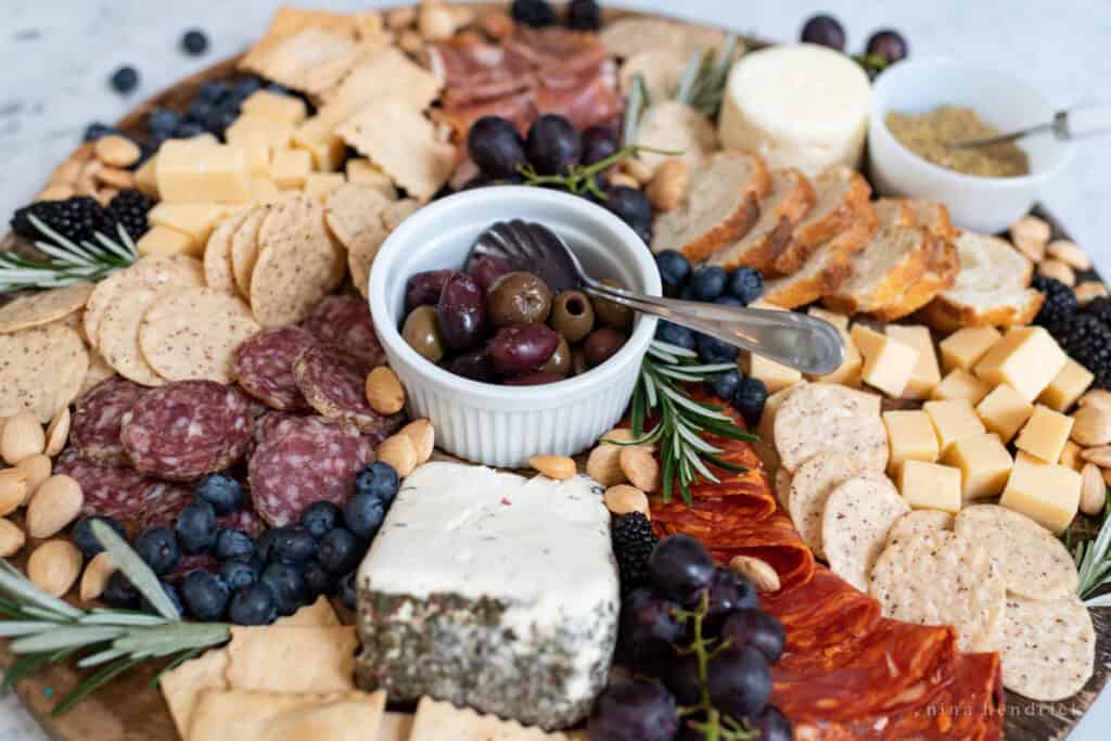 How to make a perfect charcuterie board with crackers, cheese, meat, olives, and nuts