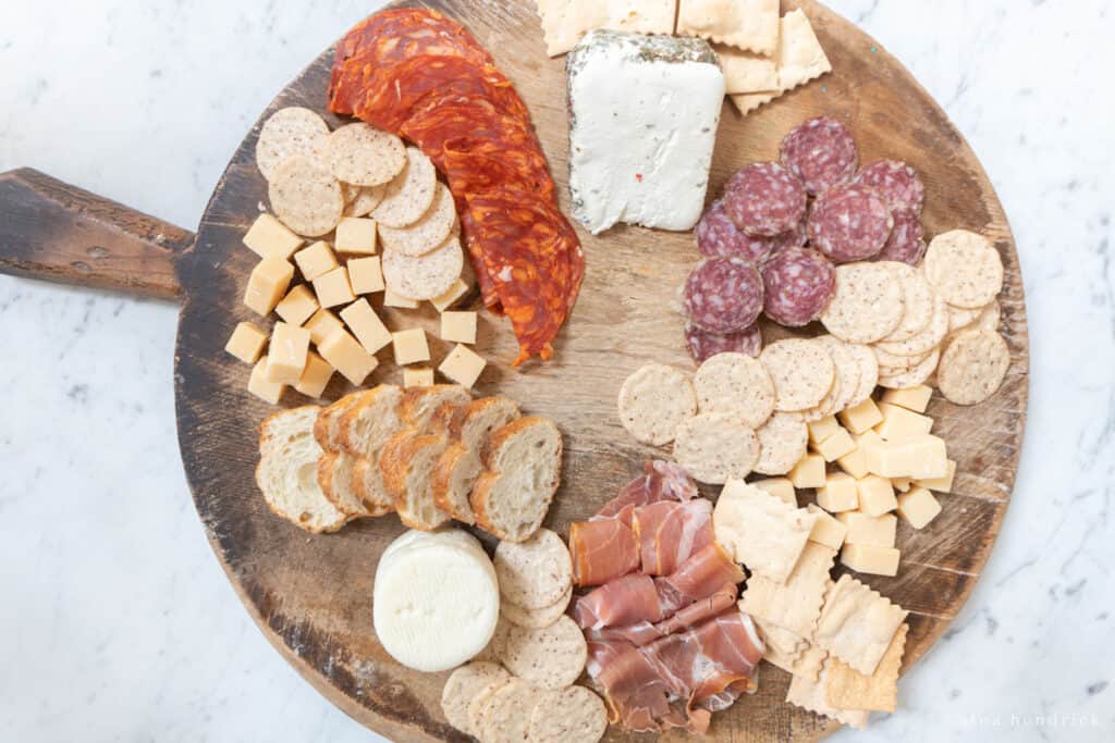 Crackers and bread with meat and cheese on a wooden board