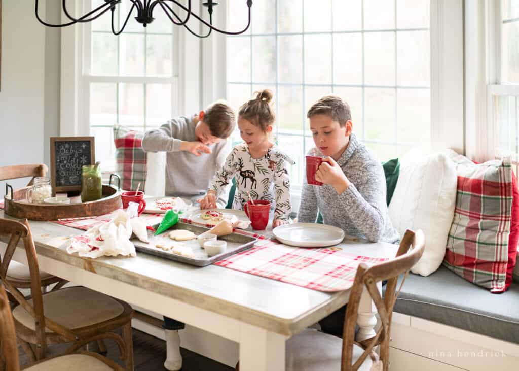 Children decorating Christmas cookies and drinking hot chocolate