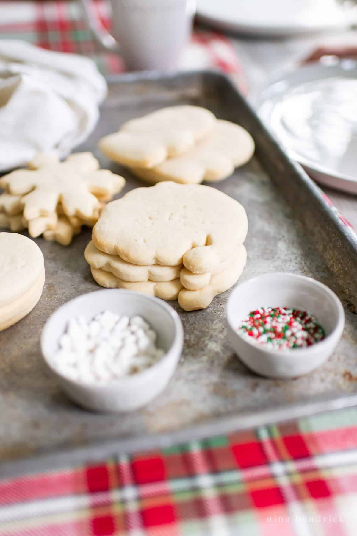 Christmas cookies supplies on a metal tray with sprinkles and other decorations