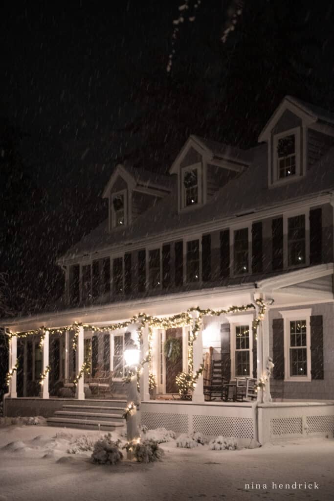 New England Colonial with Farmer's Porch and Christmas Lights on a snowy night