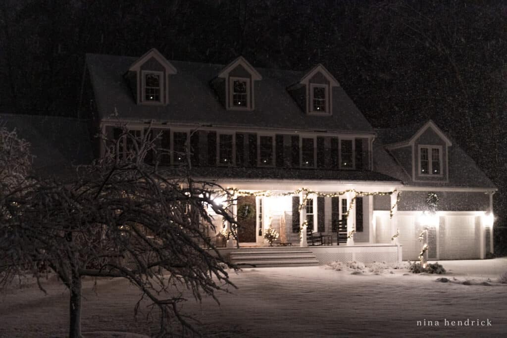Colonial with farmer's porch, garland, and candles in the window.