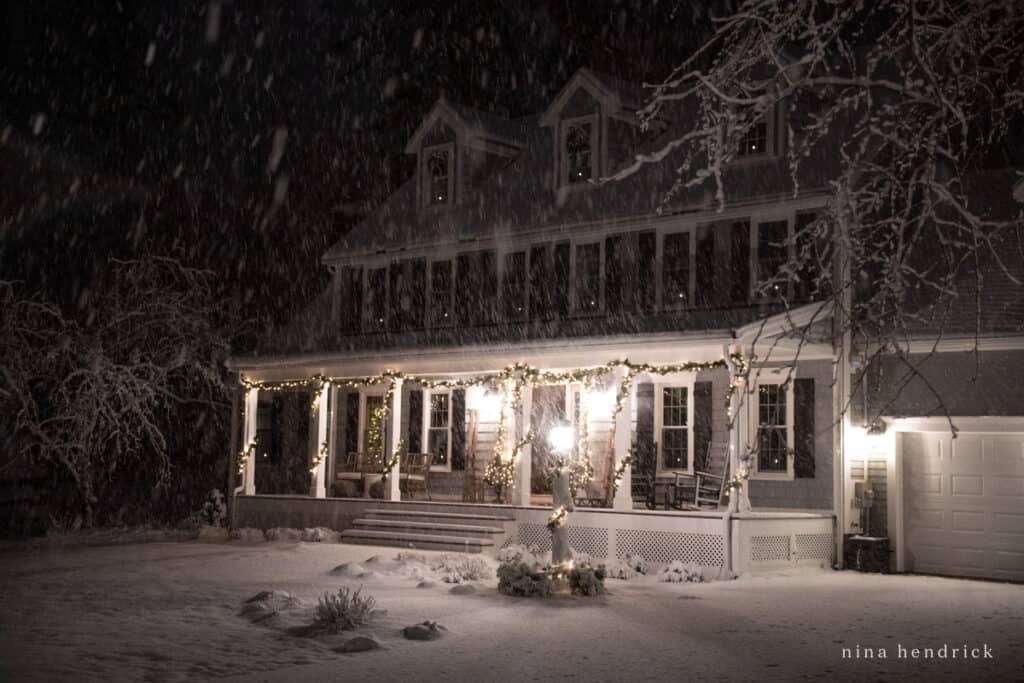 New England Colonial with garland around the posts of the farmer's porch and Christmas lights
