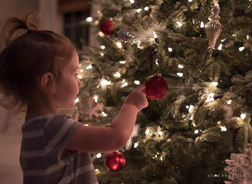 Little girl reaching for a red glittery ornament
