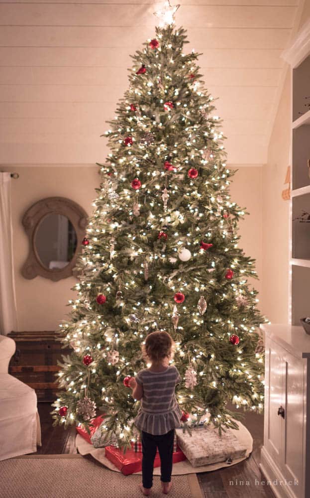 Christmas nights at light, child in front of Christmas tree with red ornaments