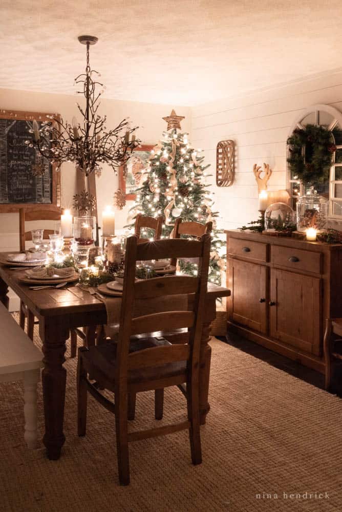 Dining room at night with Christmas tree and lights with candlelit tablescape