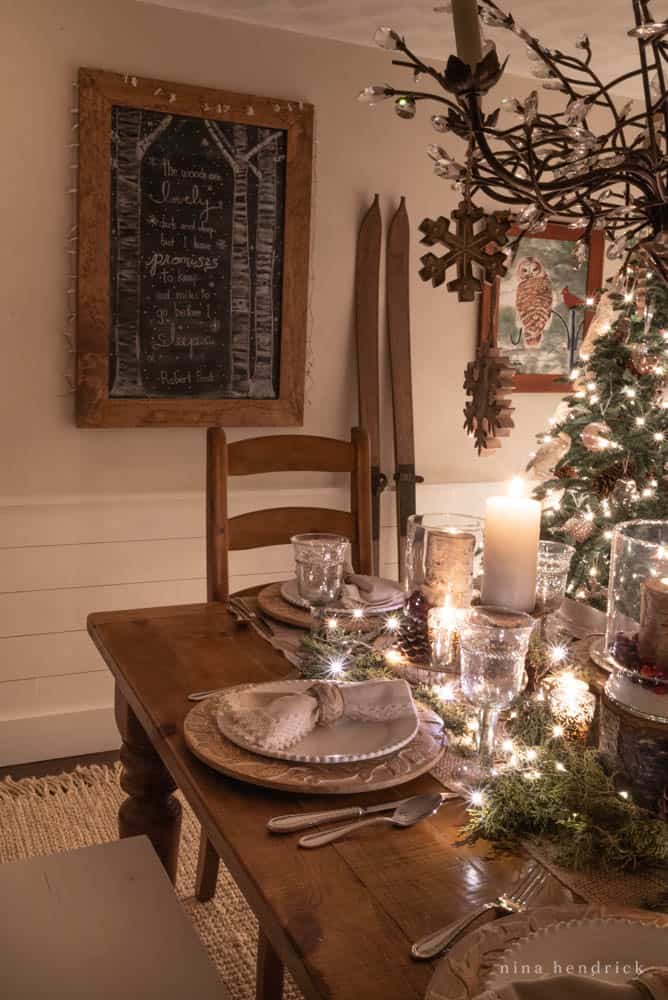 Dining room tablescape at night with Christmas lights glittering and Robert Frost poem chalkboard ard