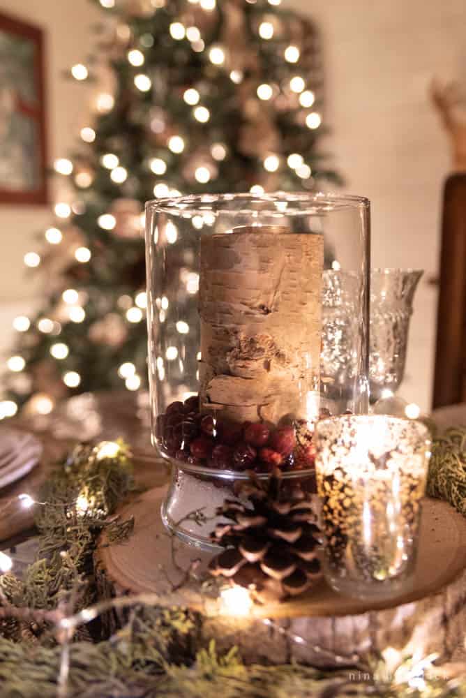 Glass hurricane with a birch bark candle and cranberries