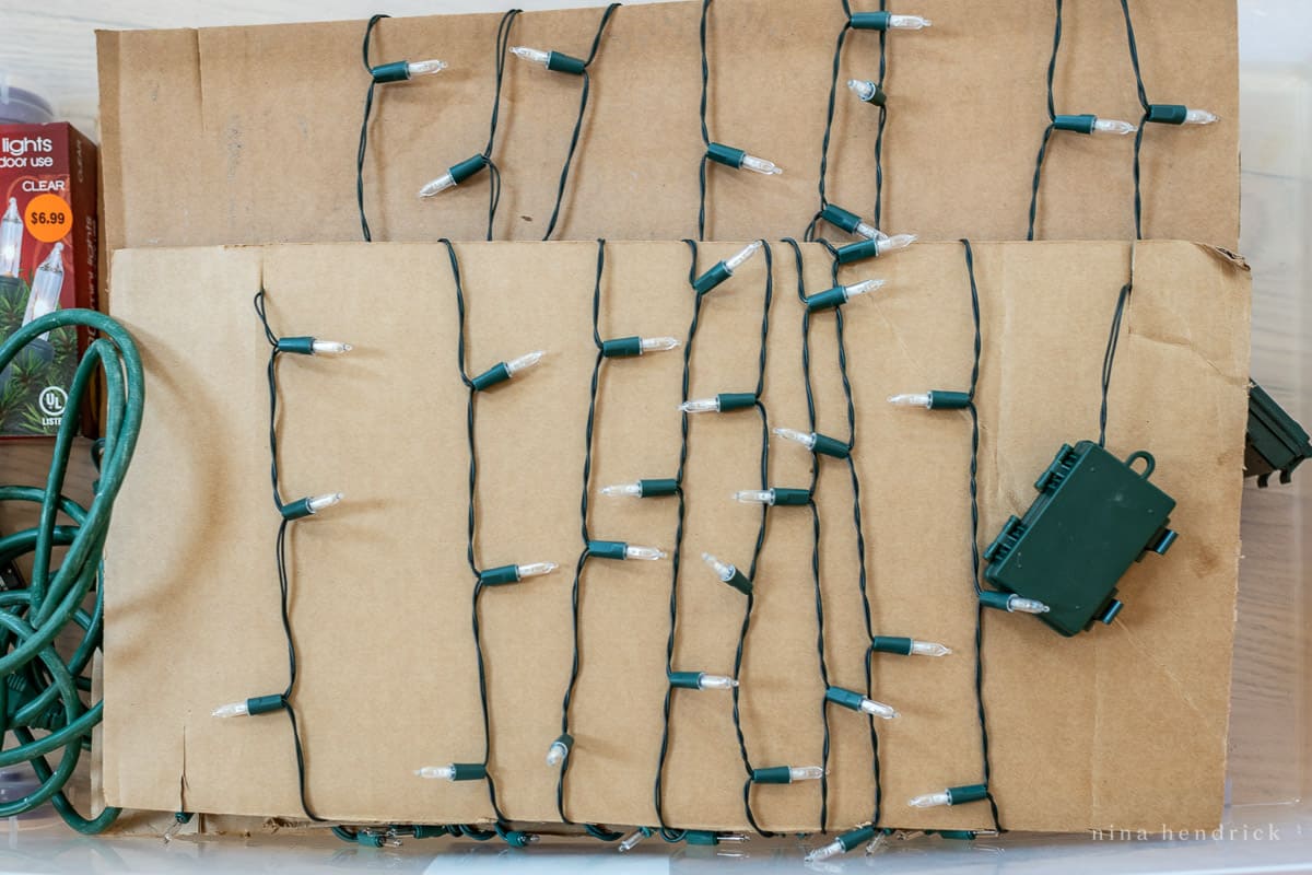 Christmas lights organized and wound around cardboard in a storage bin