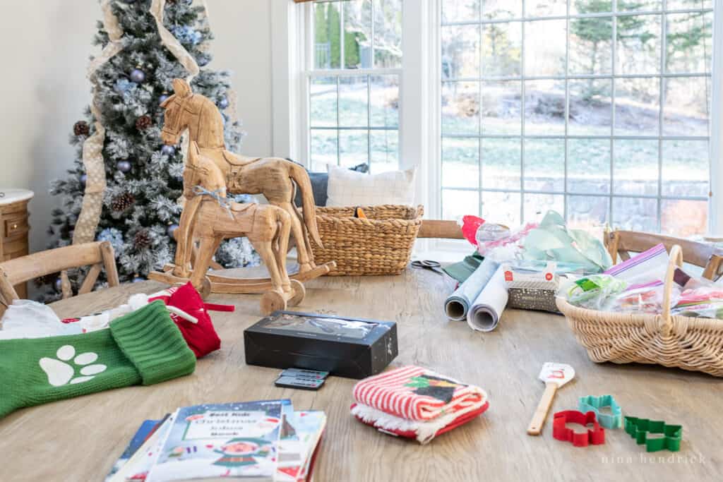 Christmas decor on a bleached wooden table with a tree in the background