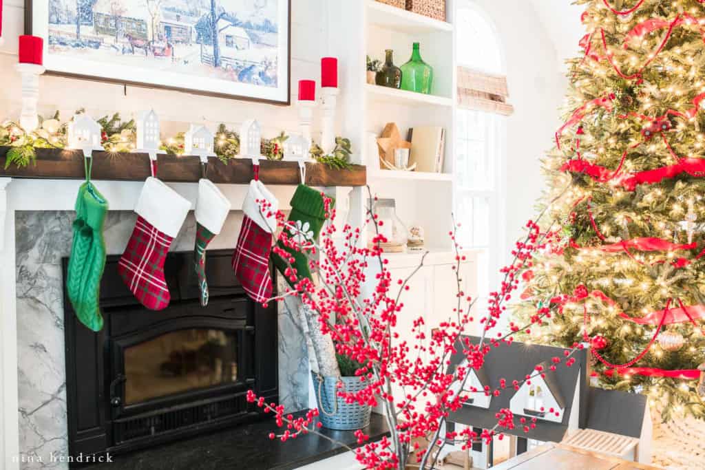 Red and green traditional Christmas decor with a rustic wood mantel.