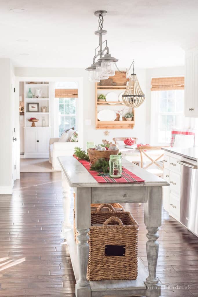 Kitchen console with baskets and a dark wood floor with red decor accents through the space