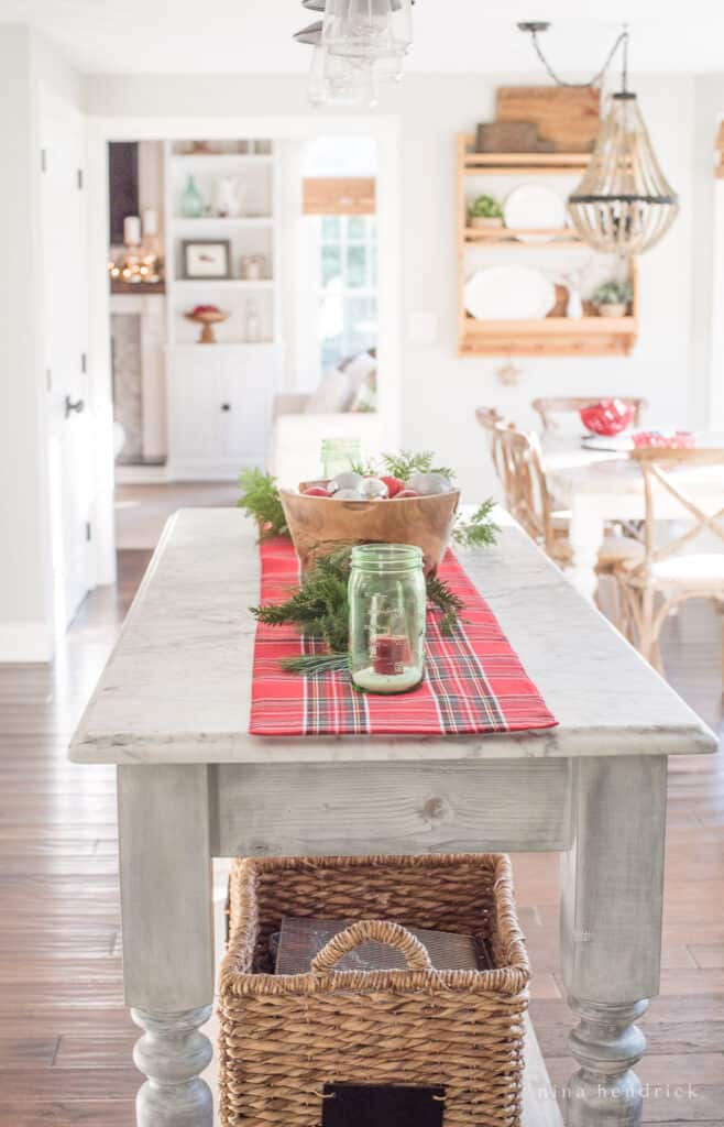 Kitchen island with a holiday centerpiece over a red runner with green mason jars and red candles