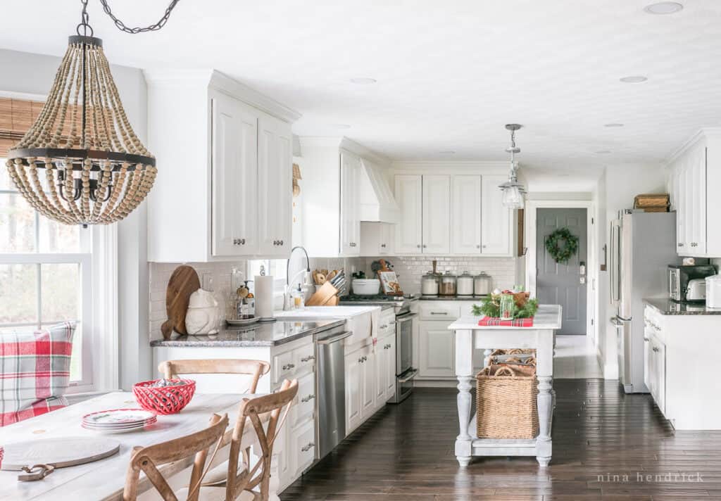 Zoomed out view of a kitchen decorated for Christmas with red and wood accents and dark wood floors