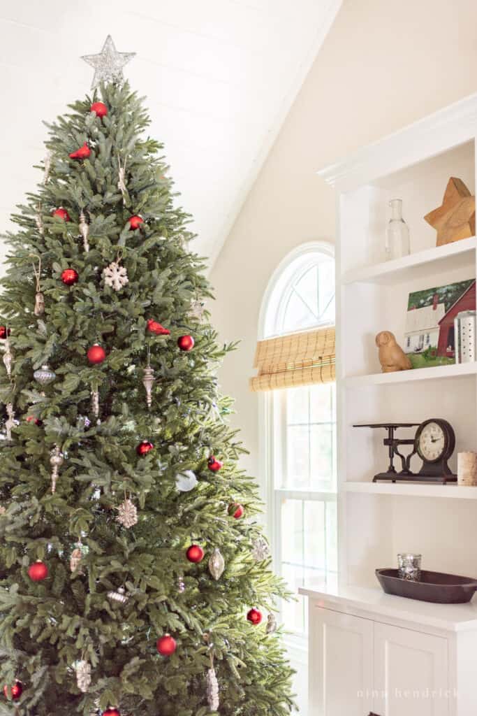 Classic Christmas decorations on family room built-ins beside an evergreen Christmas tree