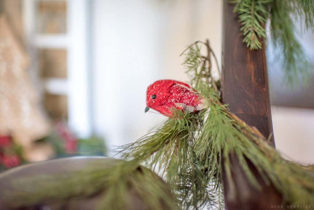 Small red bird figurine on a evergreen garland wrapped around a railing