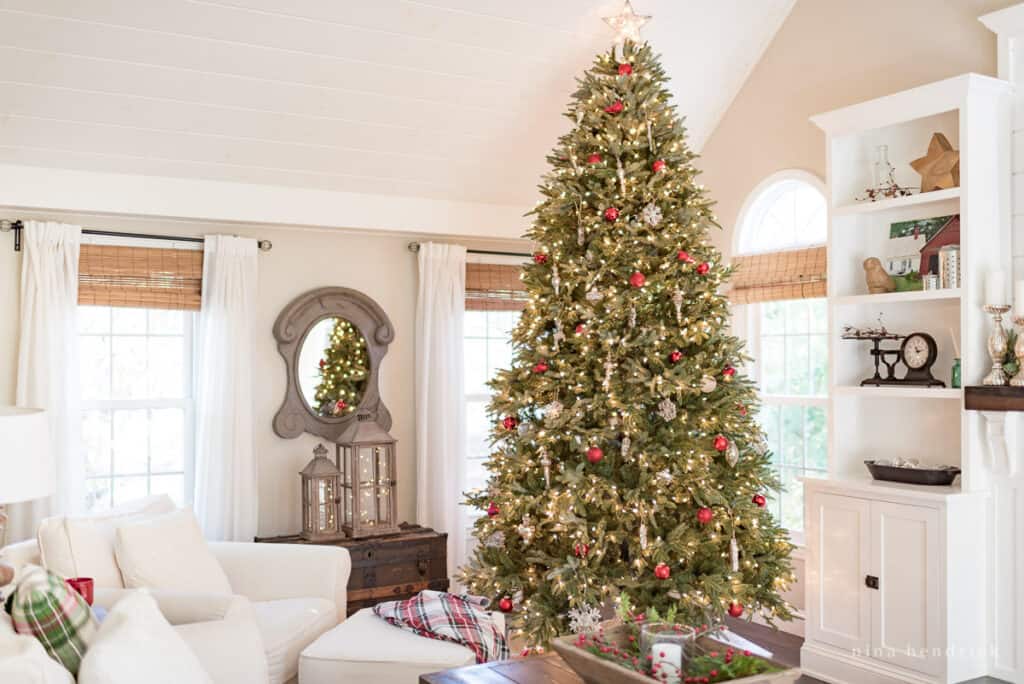 Large Christmas tree in a white family room with cozy chairs and twinkle lights