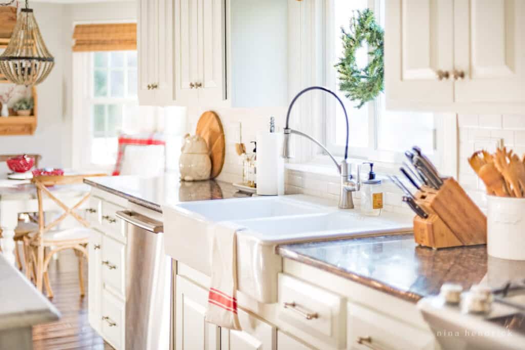 Kitchen sink with a red striped towel and a faux evergreen wreath in the window above