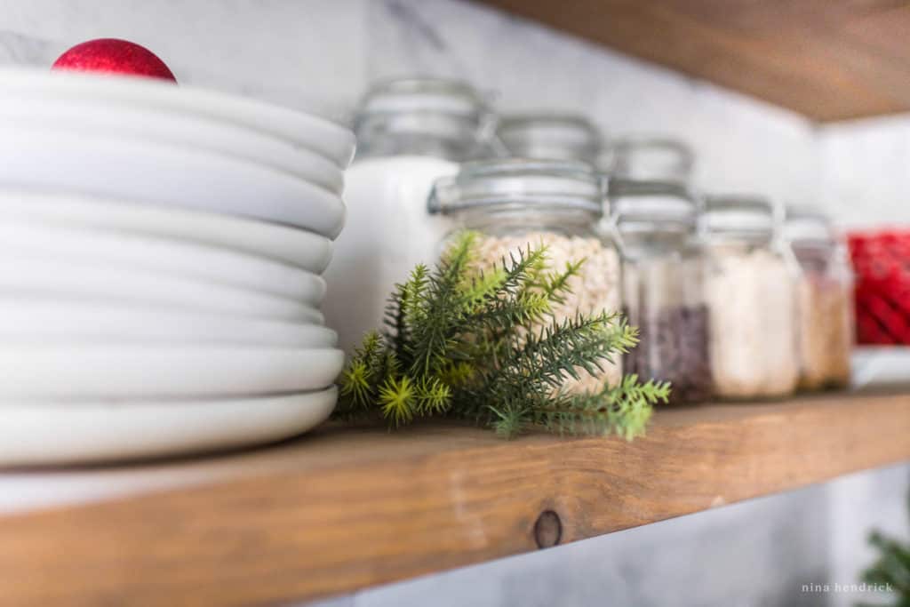 A sprig of greenery on a kitchen shelf decorated for Christmas. 