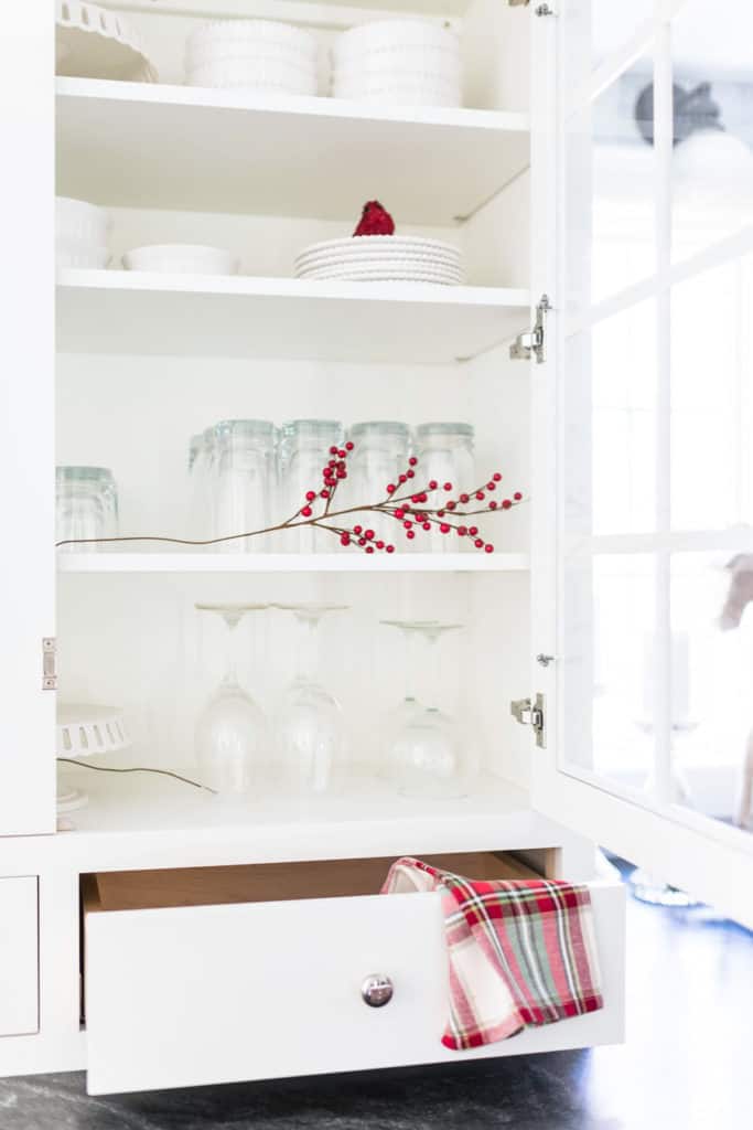 White Kitchen Hutch decorated for Christmas with a red and green plaid napkin. 