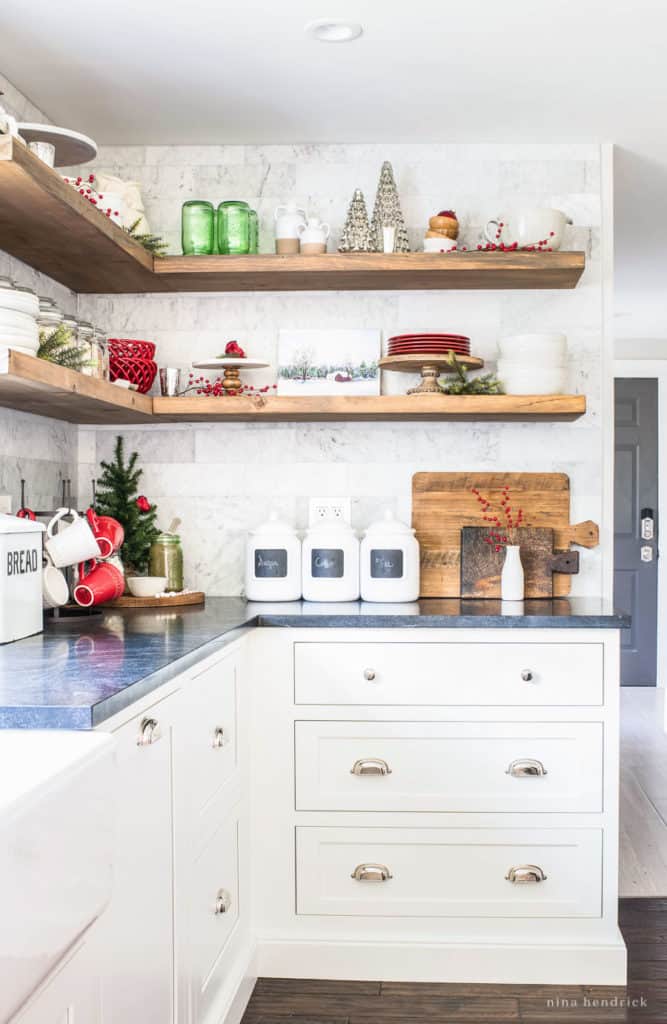 Rustic Christmas Kitchen decor with wooden shelves and cutting boards and pops of red berries.