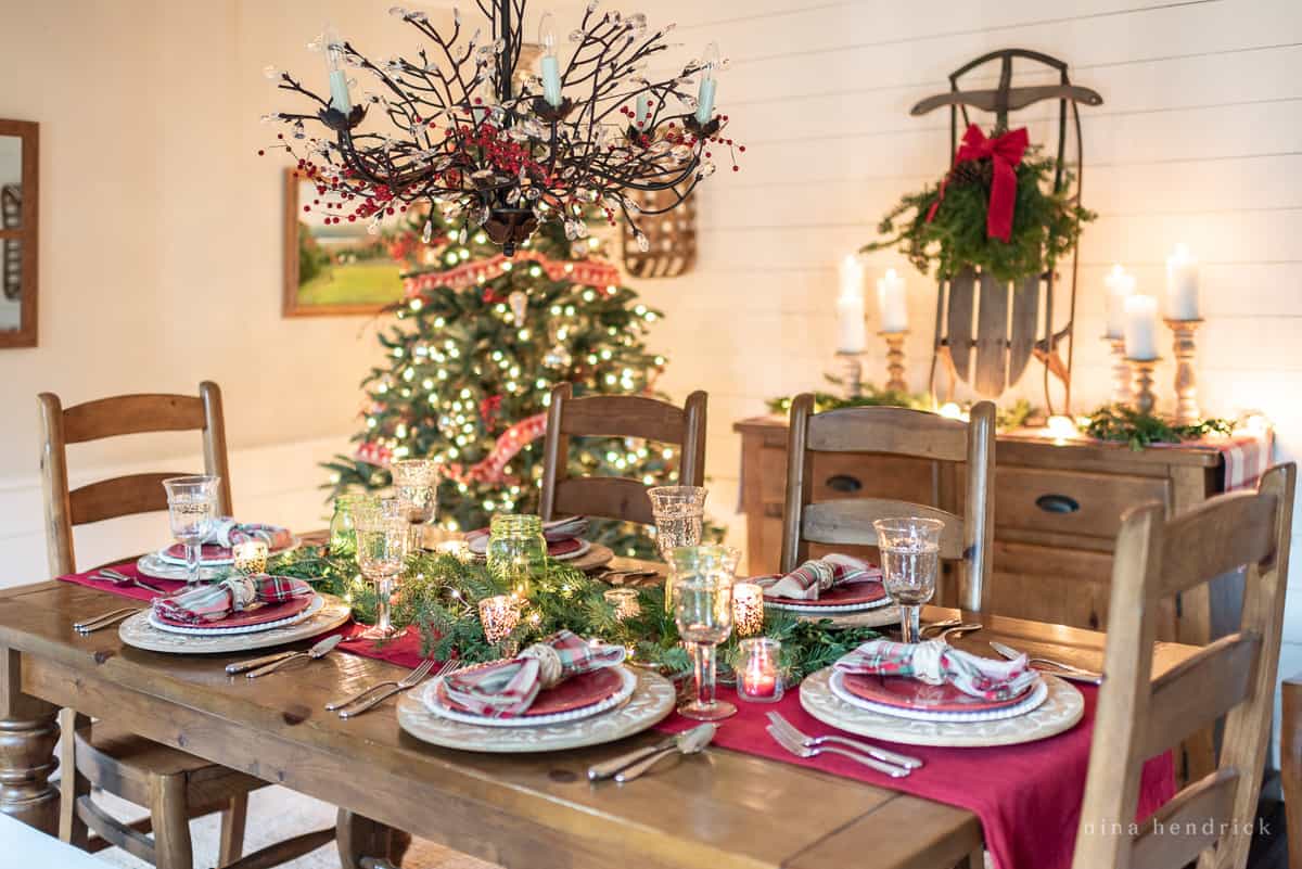 Classic Christmas table setting in the dining room with red and green accents and a vintage sled