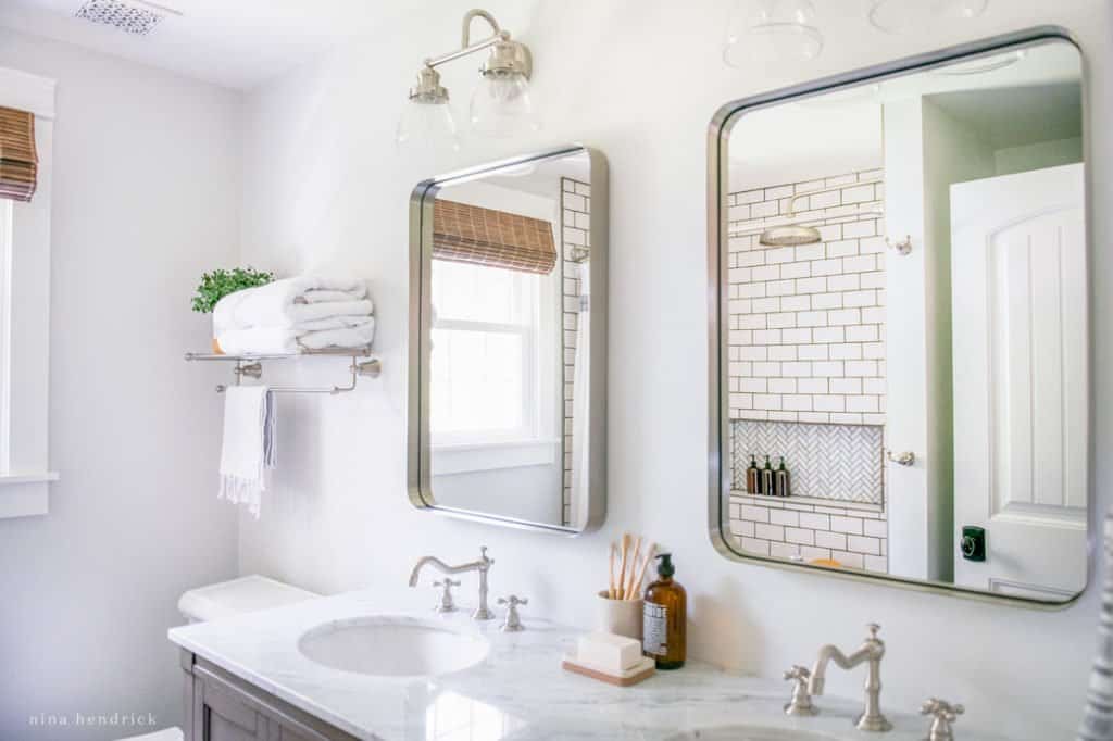 Rounded rectangle polished nickel mirrors add light to a small bathroom makeover.