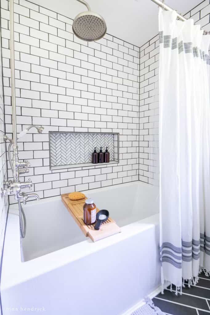 DIY replacement shower with a subway tile surround and herringbone marble niche in a small bathroom makeover.