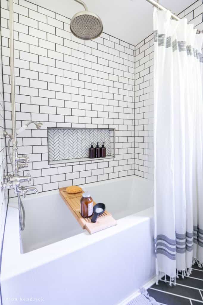 DIY replacement shower with a subway tile surround and herringbone marble niche in a small bathroom makeover. 