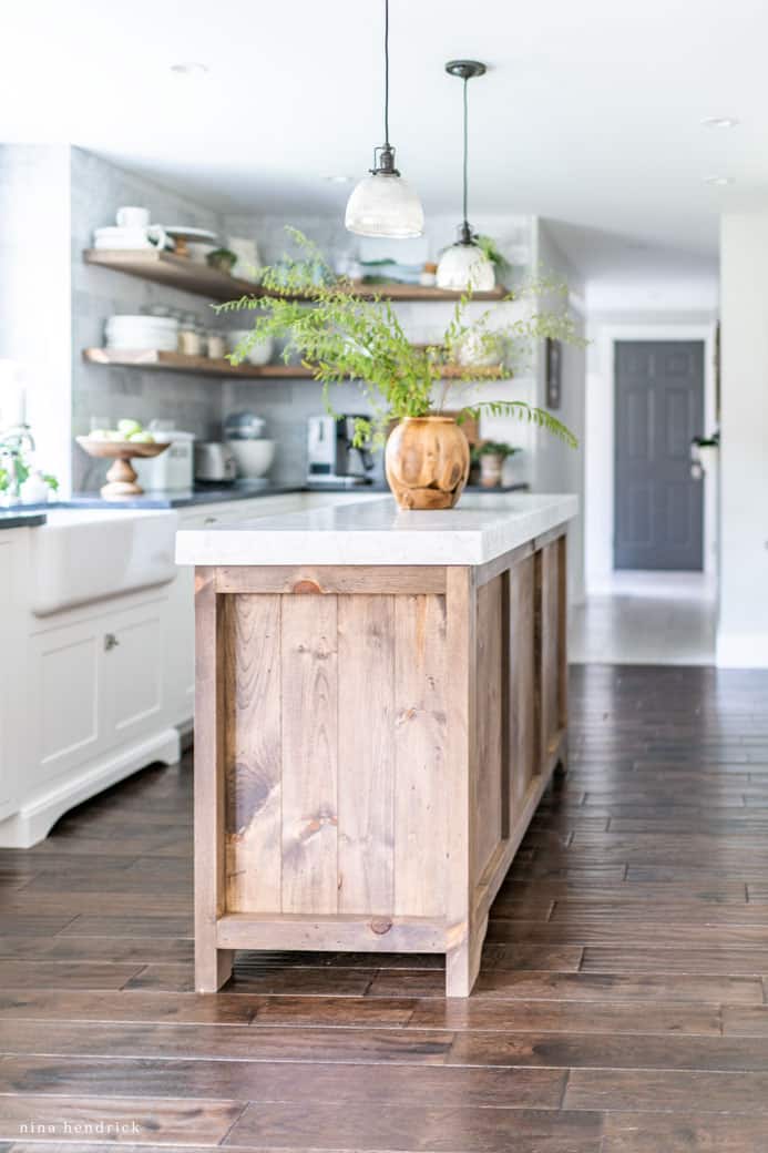 warm wood stained kitchen island with a wooden vase and greenery