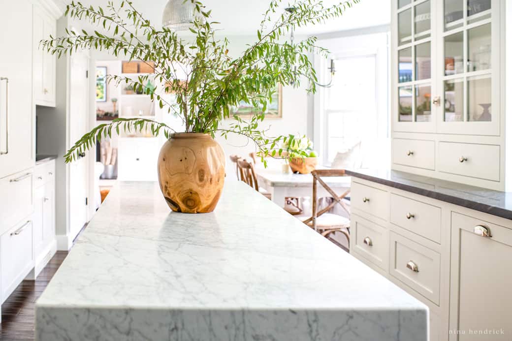 White Carrara marble countertop with a wooden vase and greenery