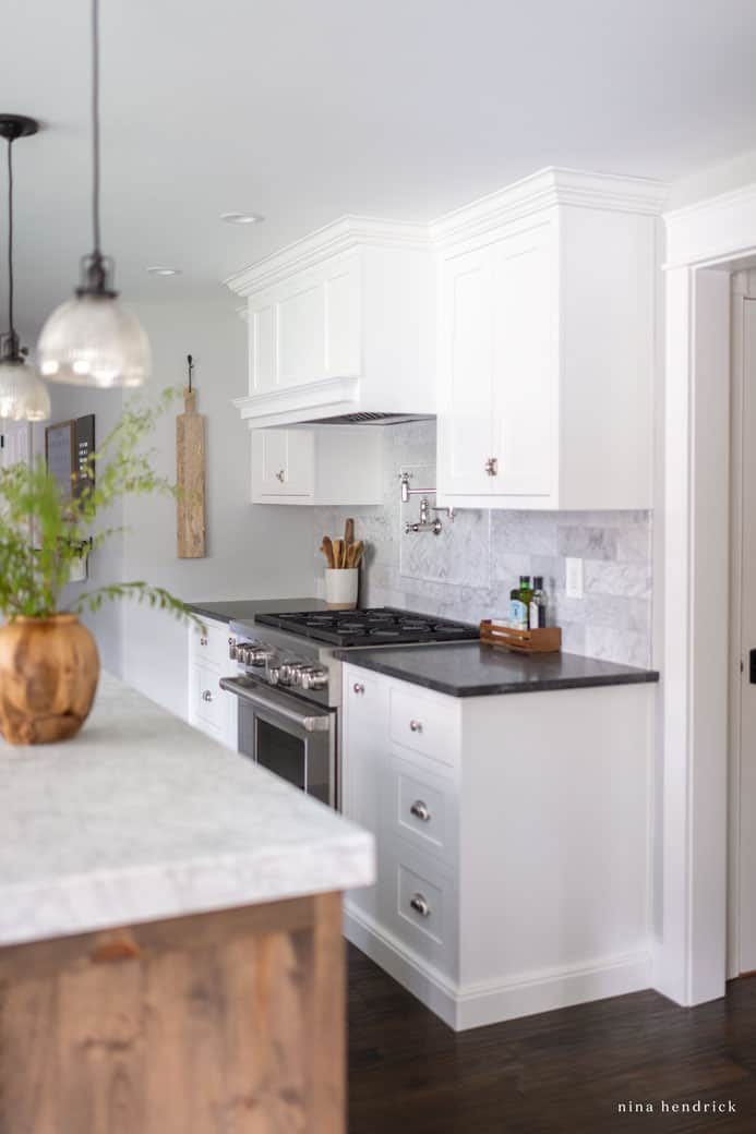 White cabinets with dark floors and countertops with stainless steel range