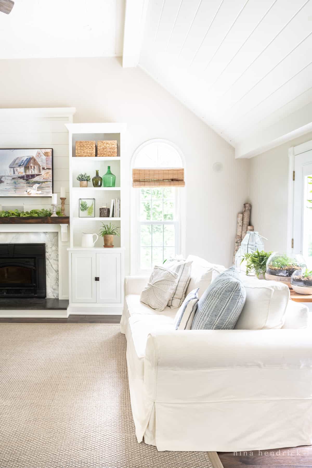 Family room with a clean white slipcovered sofa and a fireplace with marble and a white-painted surround