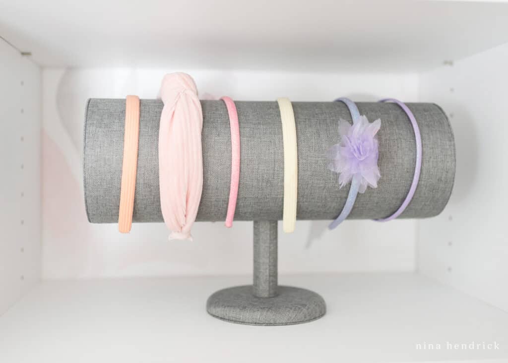 gray fabric headband organizer on a closet shelf with colorful headbands